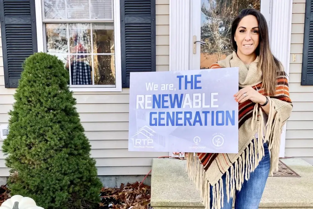 Woman holding sign promoting renewable generation and solar power in Rhode Island.