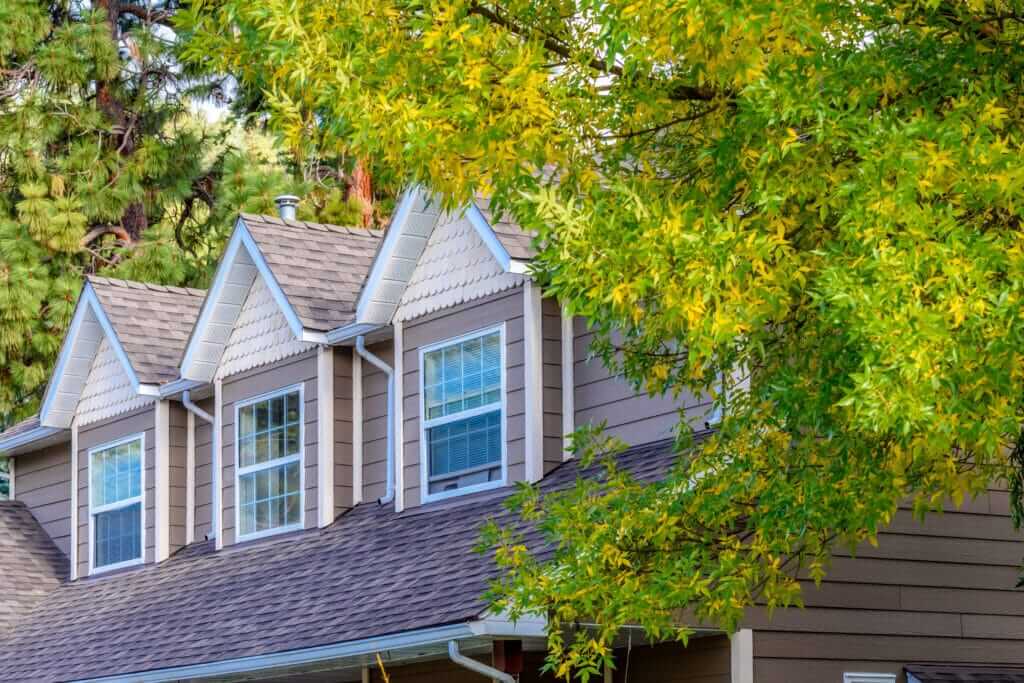 Residential solar panels on a house roof with green trees.