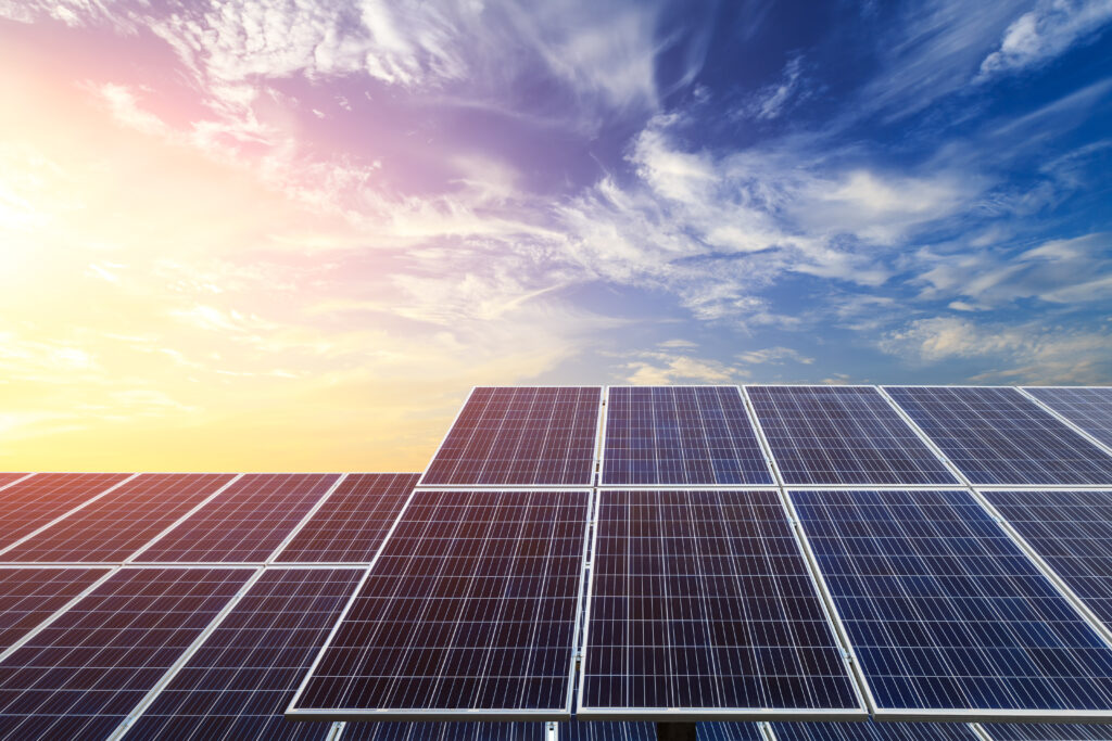 Solar panels on a rooftop against a bright sky and clouds, renewable energy solutions.