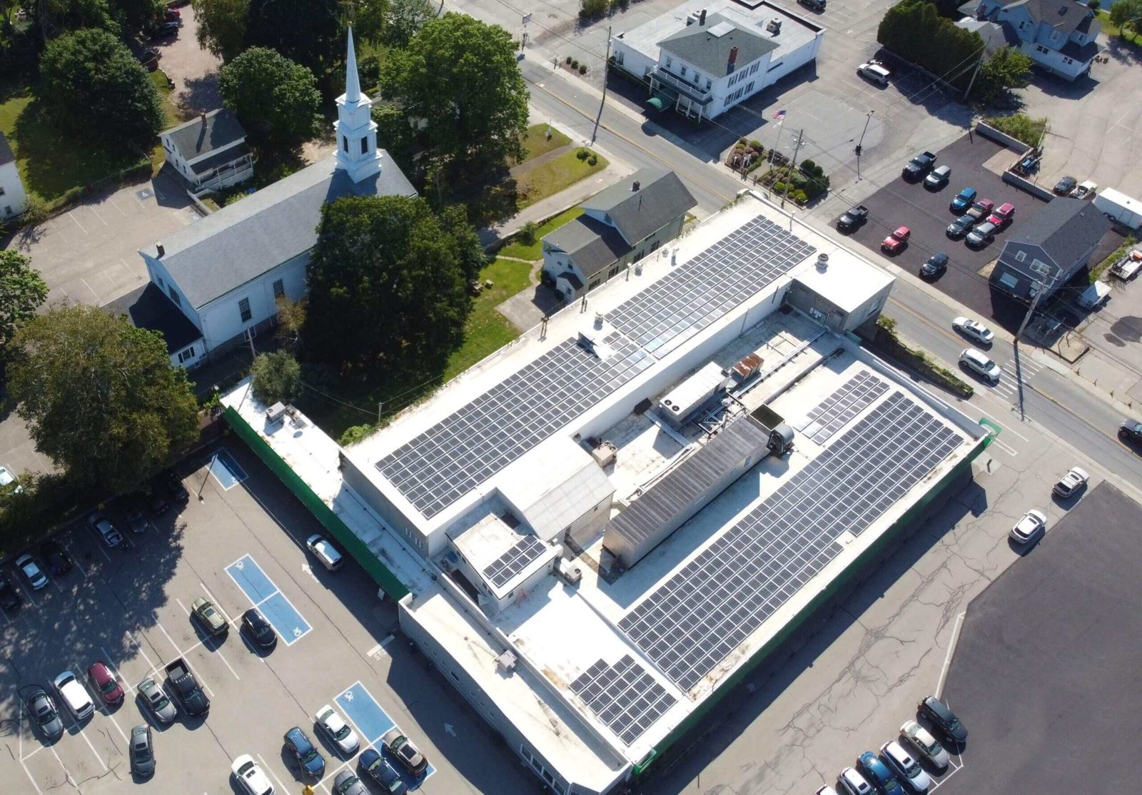 Aerial view of a Rooftop Power commercial solar array installed across a grocery store rooftop in New England