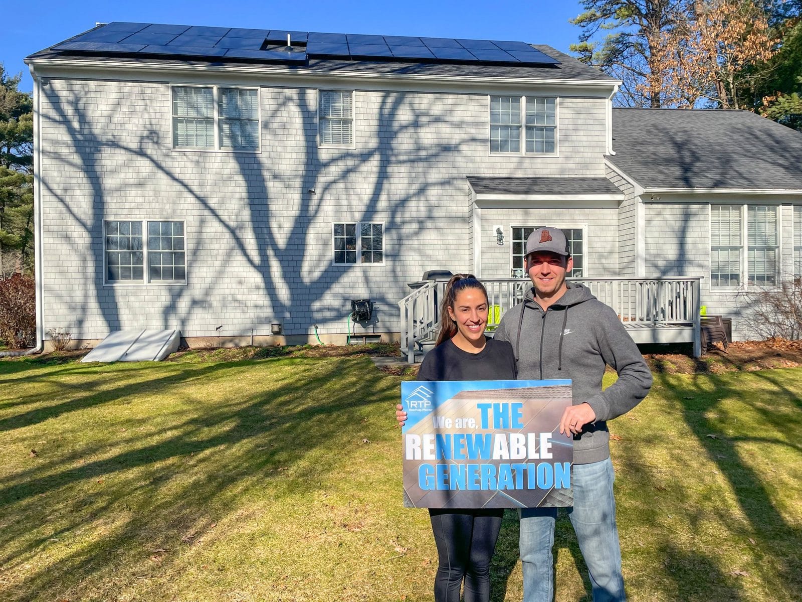 Rooftop Power solar panel installation in North Kingstown, Rhode Island, with homeowners and "The Renewable Generation" sign