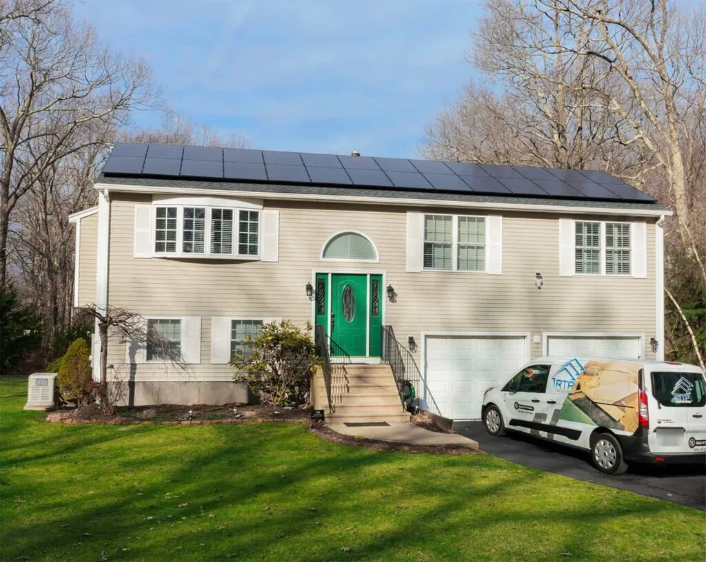 A Rooftop Power branded service van parked in the driveway of a tan raised-ranch home with a full black solar panel array covering the roof.